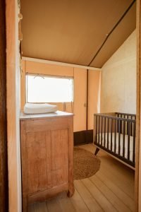 De Glastonbury safaritent heeft een slaapkamer voor de kleinsten met een ledikant en een commode.