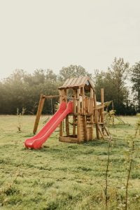 een speeltoestel met glijbaan in het gras op een glamping geschikt voor kleine kinderen
