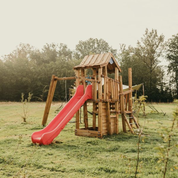 une aire de jeux avec toboggan dans l'herbe, dans un glamping adapté aux jeunes enfants