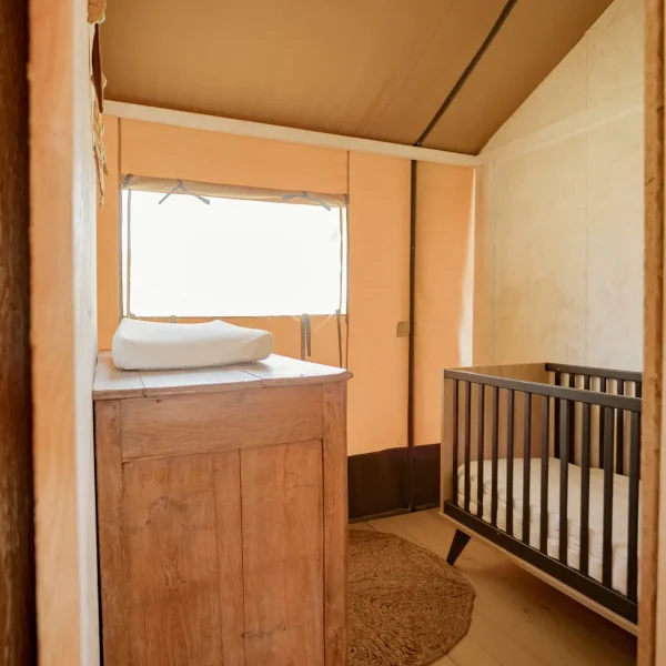La tente safari Glastonbury dispose d'une chambre pour les plus jeunes avec un lit d'enfant et une commode.