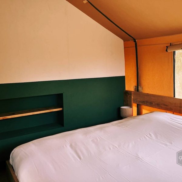 Chambre des parents dans la tente safari Fuji Rock, avec un lit impeccablement fait et des veilleuses qui créent une ambiance chaleureuse
