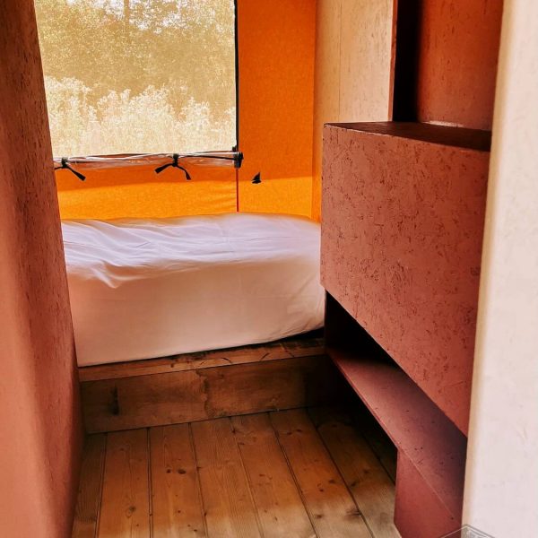 Un coin nuit douillet avec un lit confortable dans l'intérieur en bois de la tente safari Fuji Rock