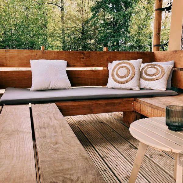 Canapé de salon en bois avec coussins sur la terrasse couverte de la tente safari glamping Fuji Rock