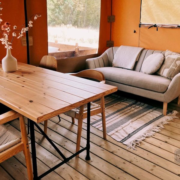 Un coin repas chaleureux et un coin salon confortable à l'intérieur de la tente safari glamping Fuji Rock