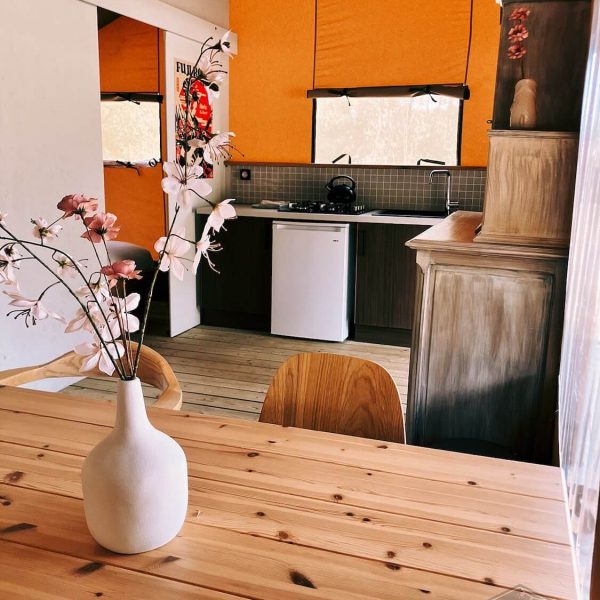 Vue depuis la table à manger en bois sur la cuisine ouverte équipée et le placard de la tente safari Fuji Rock