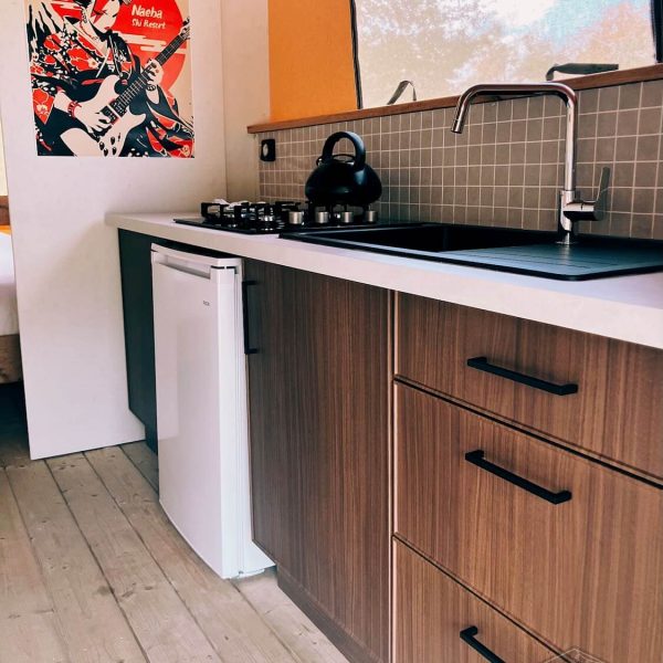 Cuisine ouverte haut de gamme dans la tente safari Fuji Rock, équipée d'une plaque de cuisson à gaz, d'un évier noir et d'un réfrigérateur